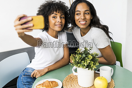 Zwei Gl Ckliche Freundinnen Sitzen Am Tisch Und Stockfoto