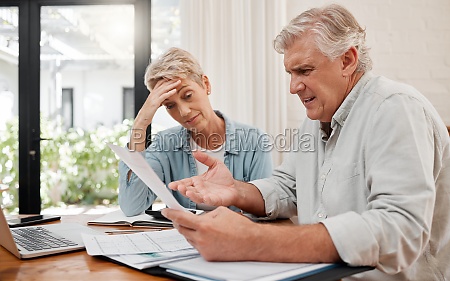 Sad retirement couple,  finance debt and anxiety in financial planning,  mortgage home loan and paper bills. Stress woman,  angry man and senior people pension problem,  admin crisis and budget mistake.