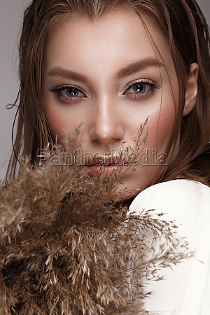 Beautiful woman with classic nude make-up,  light hairstyle and dry flowers. Beauty face. Photo taken in studio