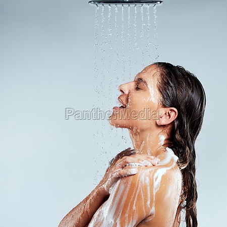 Singing in the shower. a young woman taking a shower against a grey background