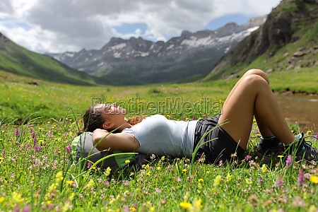 Side view portrait of a hiker resting on the grass in a valley