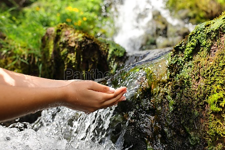 Close up of a woman hands catching water from creek