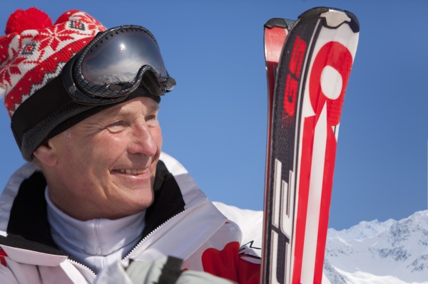 smilende mand staende holding ski
