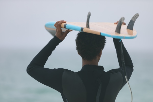 surfista masculino cargando tabla de surf