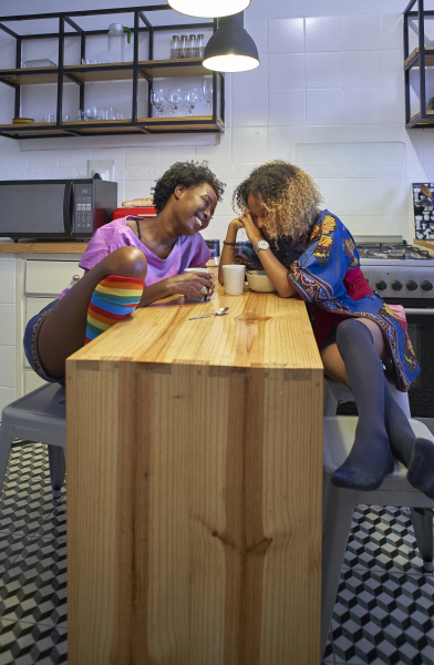 duas mulheres felizes sentadas na cozinha
