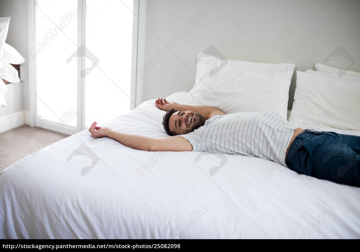 Hombre acostado en la cama con los brazos levantados - Stockphoto #25082098  | Agencia de stock PantherMedia