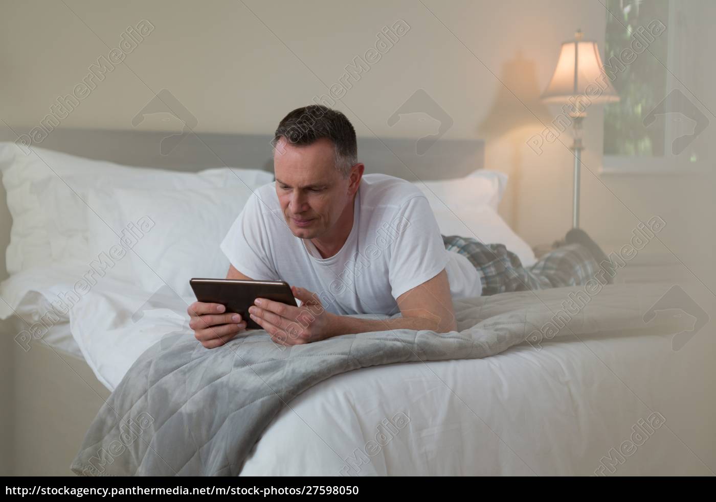 Hombre acostado en la cama y usando la tableta digital - Stockphoto  #27598050 | Agencia de stock PantherMedia