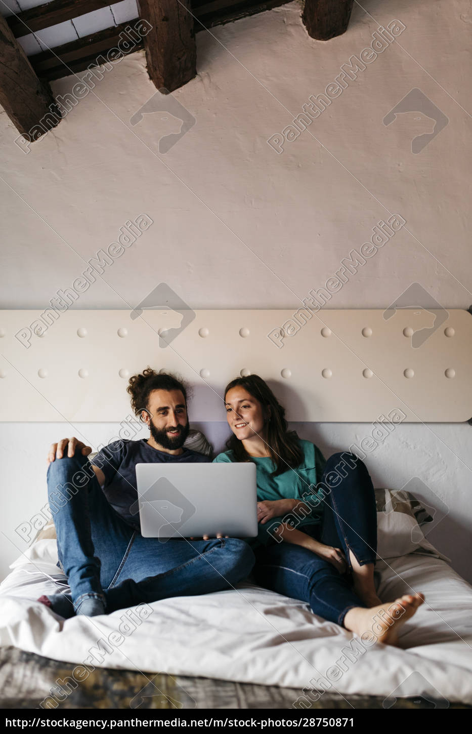 Pareja viendo película sentada en la cama en casa - Foto de archivo  #28750871 | Agencia de stock PantherMedia